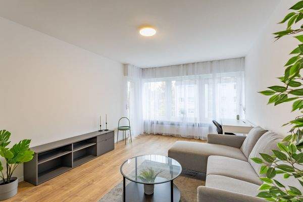 Helles Wohnzimmer mit großer Fensterfront und Zugang zur Loggia