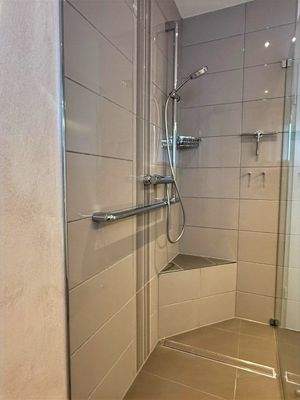 große Dusche und helle Fliesen