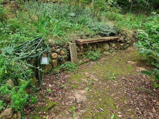 Steinmauer mit Bank und Wasseranschluß