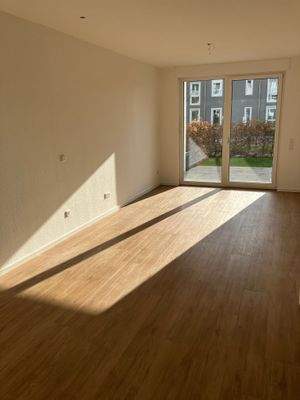 Blick in den Wohnbereich, weiß angelgte Wände, brauner Vinyl-Designboden und Zugang zur Terrasse