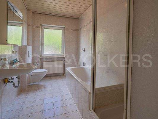 Badezimmer mit Wanne, Dusche und Waschmaschinen-An