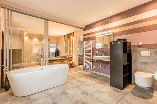 Masterbad mit verstellbarer Glasfront, freistehender Badewanne, ebenerdiger Dusche, WC, Waschtisch und Urinal 