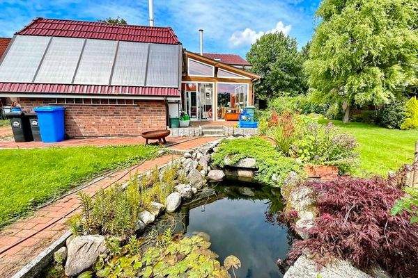 Blick vom Teich auf das Grundstück mit Wintergarten