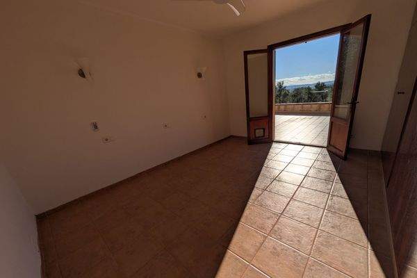 Helles Schlafzimmer mit Zugang zur Terrasse und Blick in die Natur