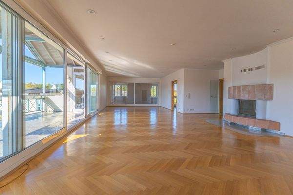 Großes Wohnzimmer mit Kamin und Zugang zum großen, überdachten Balkon  