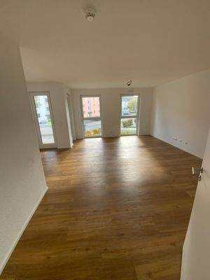 Wohn- und Essbereich mit weißen Wänden, Vinylboden in Holzoptik und Fenster.JPG