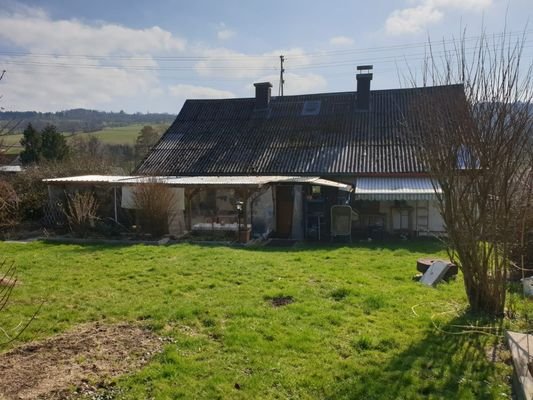 Blick vom Garten auf das Einfamilienhaus mit überdachter Terrasse