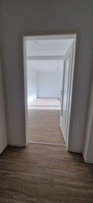 Flur mit Blick ins Wohnzimmer, heller Vinylboden, weiße Wände.jpg