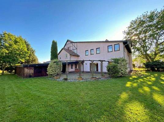 Blick aus dem Garten auf die große Terrasse und das Haus