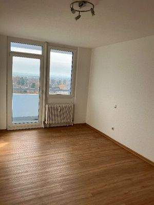 Ansicht des Schlafzimmers mit weißen Wänden, Design-Vinylboden in Holzoptik, sowie einer Balkontür mit Zugang zum Balkon.