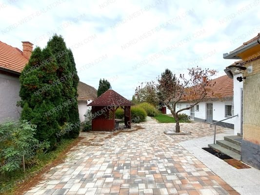 Außenansicht mit gepflastertem Hof und Pavillon