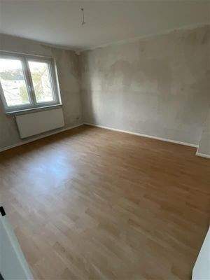 Zimmer mit Laminatboden und Fenster