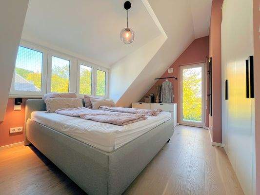 Schlafzimmer mit großer Fensterfront und Balkon
