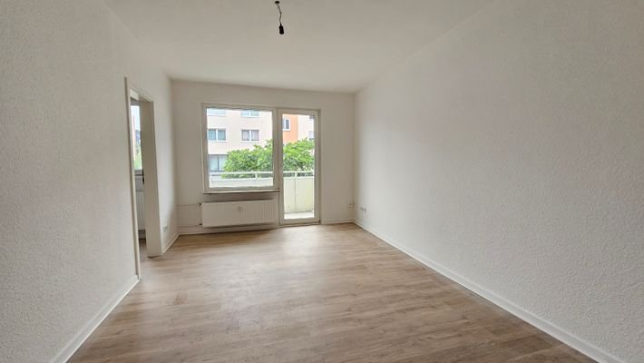 Wohnzimmer mit angrenzender Küche und Balkon 