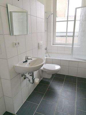 gefliestes Bad mit Wanne und Fenster