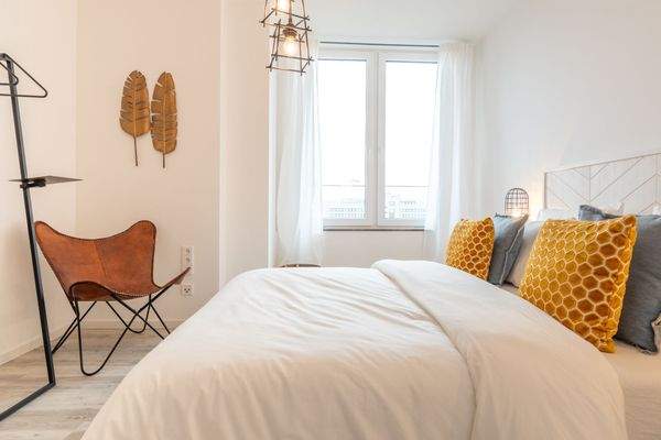 Beispiel eines eingerichteten Schlafzimmers mit weißen Wänden und Decke und holzfarbenen Vinylboden