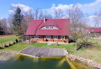 Ansicht des Schrotholzhauses mit Terrasse uns Schwimmteich