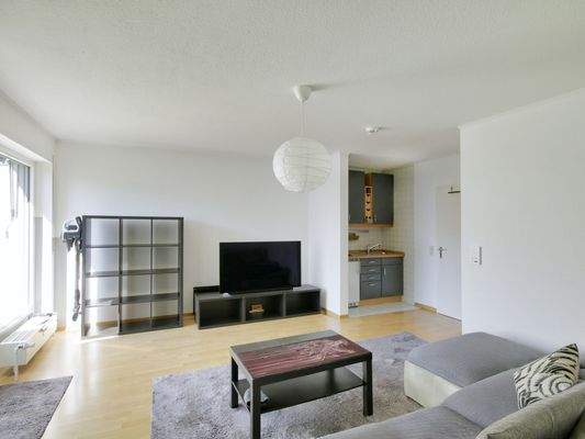 Offen gestalteter Wohnraum mit Küchenzeile und Balkonzugang