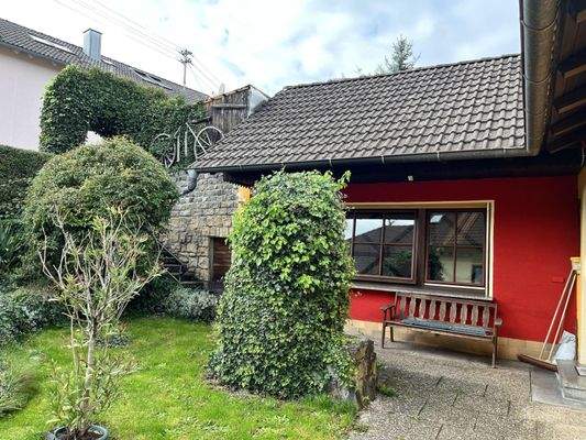 überdachte Terrassenfläche mit Steinplattenweg im Garten