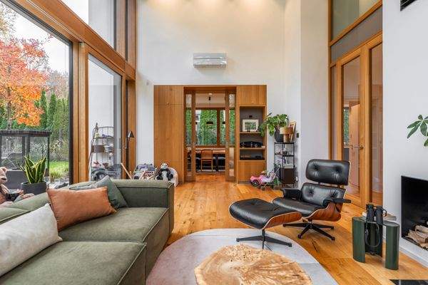 Lichtdurchfluteter Wohnbereich mit einem Sofa auf der linken Seite und einem bewuemen Sessel auf der rechten Seite