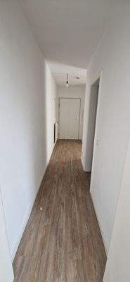 Blick in den Flur vom Schlafzimmer, rechts abgehend das Bad. Heller Vinylboden, weiße Wände.jpg