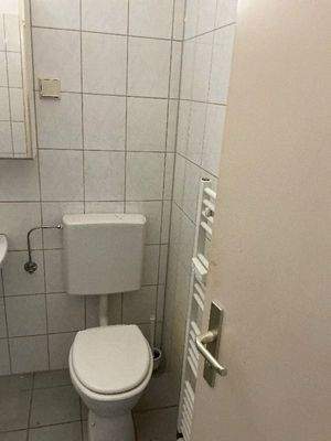 Weitere Ansicht des Badezimmers mit weißem Stand-WC, sowie weißem Handtuchheizkörper.