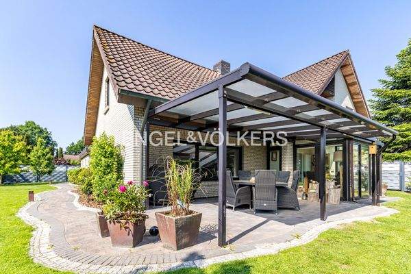 Die Seienansicht mit überdachter Terasse inkl. der hochwertigen Sitzgruppe, Wintergarten und darüberliegender Loggia