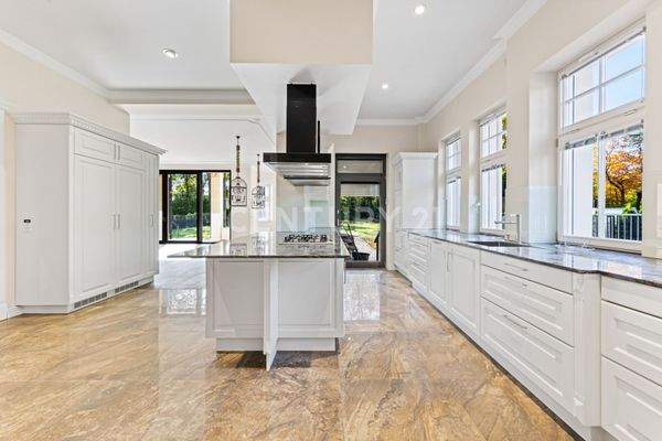 Luxuriöse Wohnküche mit Kochinsel und Blick ins Grüne