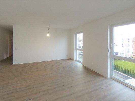 Wohnbereich mit 2 bodentiefen Fenstern, weiße Wände und PVC-Boden in Parkettoptik.JPG