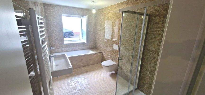 Bad mit Dusche, Wanne und Fenster im EG