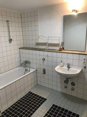 Weiß gefliestes Badezimmer mit weißen Sanitäreinrichtungen.