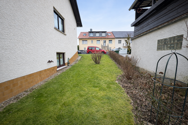 Grasweg zwischen Häusern bei Wolkenhimmel