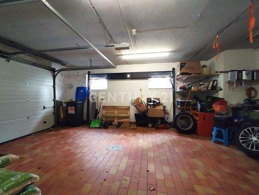 Die große geflieste Garage mit Zugang zum Kellerbereich