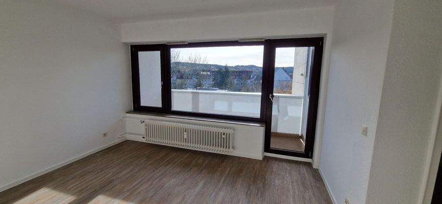 Wohnzimmer mit Blick auf Balkon, mit hellem Vinylboden und weißen Wänden (quer).jpg