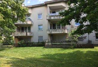 Gebäude Rückseite des mehrstöckigen Wohnhauses mit Blick in die Grünanlage mit Sträuchern