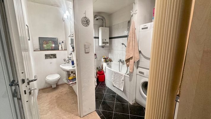 Badezimmer mit Badewanne und schwarzen Fliesen
