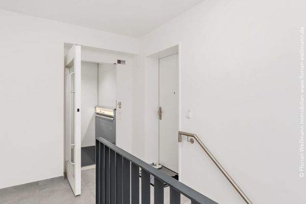 Treppenhaus mit verglastem Fahrstuhl.