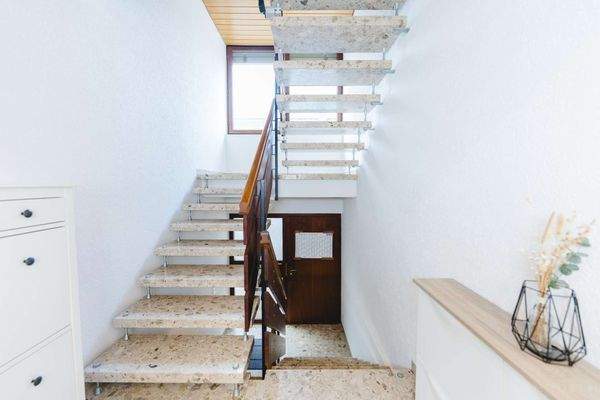 Treppenhaus mit freitragenden Steinstufen und Holzgeländer