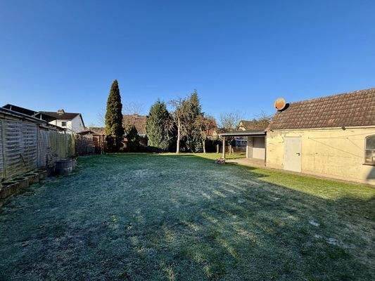 Blick in den Garten und auf das Garagengebäude mit angeschlossenem überdachten Sitzplatz