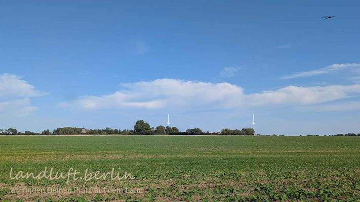 Blick von Südwesten über die Felder mit den ungefähren Ausmaßen des Grundstücks. Links erkennt man  das Gebäude der alten Windmühle.jpg