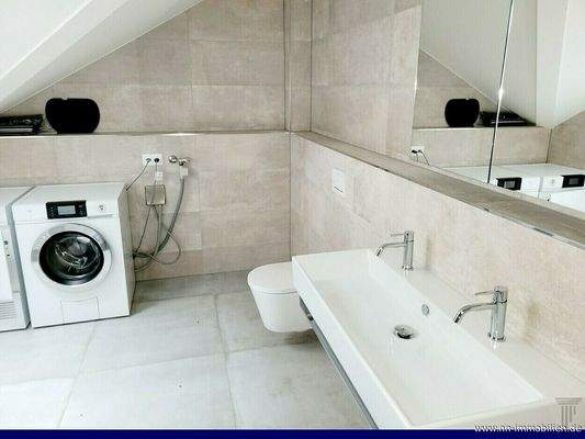 Modernes Tageslichtbad mit Doppelwaschbecken, WC sowie Waschmaschine und Tumbler.