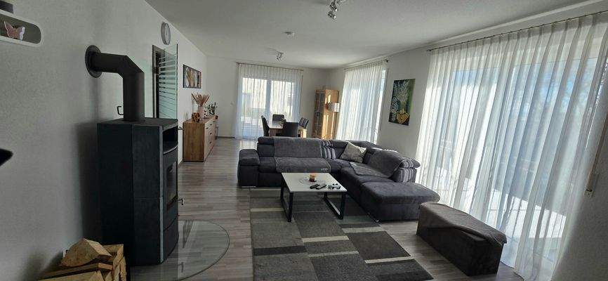 Großzügiger Wohnbereich mit integriertem Essbereich, Holzofen und Zugang zum Balkon 