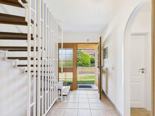 Heller Eingangsbereich mit Holztreppe und direktem Zugang in den liebevoll angelegten Garten