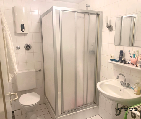 Hell gefliestes Badezimmer mit Duschkabine