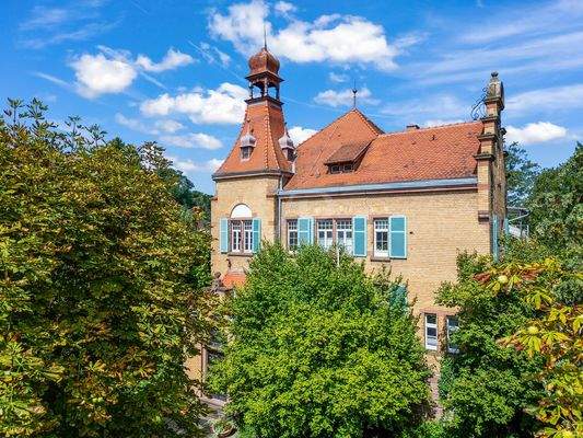  Außenansicht des Gebäudes mit historischem Turm und rotem Ziegeldach