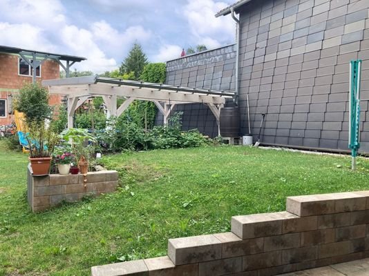 Blick in den Garten mit Freisitz und Neubau Wohnhaus im Hintergrund