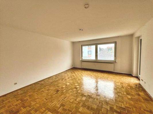 Wohnzimmer mit Parkettfußboden und Zugang zum Balkon