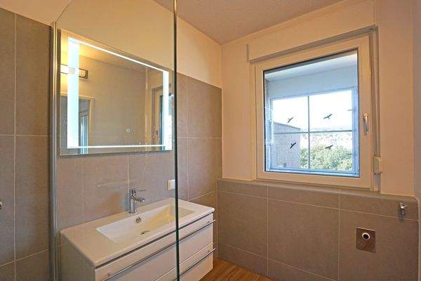 En-Suite-Bad mit Dusche, Waschtisch, LED-Spiegel, Fenster und Waschmaschinenanschluss