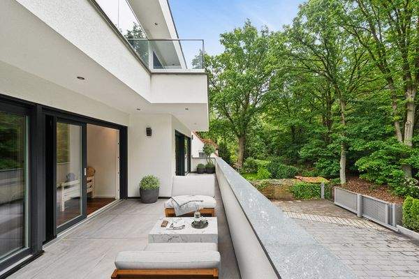 Blick auf den Südbalkon (virtuell möbliert) im ersten Obergeschoss und die gläserne Balustrade des Balkons im zweiten Obergeschoss