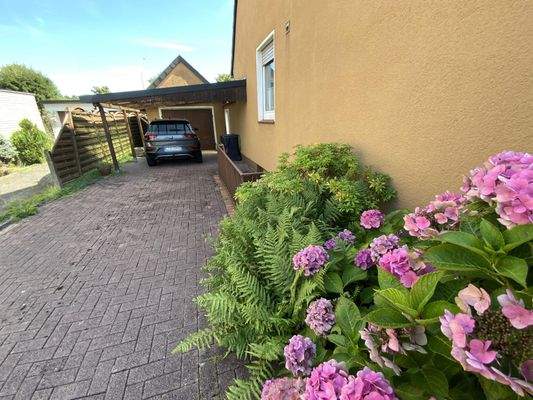 Eine Garage am Haus mit teils überdachten Stellplätzen davor
